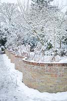 Serpentine garden wall with snow. Crinkle crankle wall.