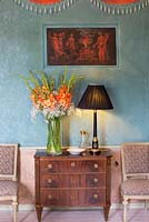 Gladiolus in vase in old house, antique lamp, Chest of Drawers, chairs