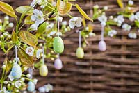 Small decorative eggs hanging from branch in blossom