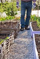 Man constructing gravel path in vegetable garden. Adding gravel. 