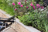 Seating area beside border of Buxus 'Vardar Valley', Foeniculum 'Giant Bronze', Rosa 'Munstead Wood'. The Cloudy Bay Garden. Designer: Wilson McWilliam Studio - Andrew Wilson - Chelsea Flower Show 2014