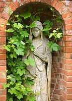 Statue of woman in niche in wall in the sunken garden. Gipsy House, Buckinghamshire
