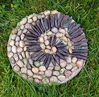 Pebble mosaic paving slab in grass - stepping stone on lawn - closeup 