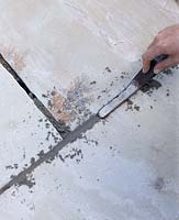 Mortar being applied to cracks with a pointing iron - paving project 