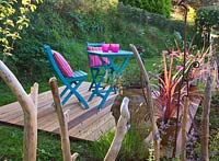 Wooden deck with blue table and chairs and pink cushions