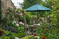 Corner of walled garden with peonies, roses and sweet williams