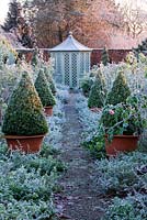 Path through the rose garden to a summerhouse with David Austin roses and terracotta containers with clipped buxus 