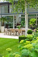 View across lawn and Hydrangea 'Annabelle' to dining area on limestone patio - The Glass House, Petersham - Architects Terry Farrell Partners - Garden design by Sallis Chandler 
 