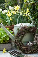 Watering can with spring flowers, fork, Easter wreath and seedlings
