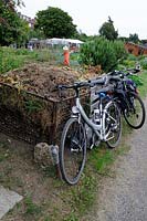 Bikes parked in front of a compost heap on allotment, Golf Course Allotments, London Borough of Haringey