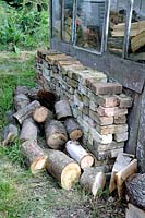 Logs of wood with bricks stacked alongside allotment shed, Golf Course Allotments, London Borough of Haringey
