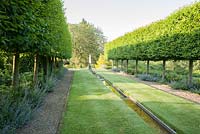Formal rill between pleached hornbeams leads to a metal obelilsk. Forest Lodge, Pen Selwood, Somerset, UK