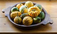 Mixed squash displayed in a wooden bowl indoors