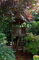 children's wooden fort under shady tree - early autumn