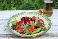 Salad leaves with edible flowers in rustic bowl - nasturiums, borage, chives and calendula