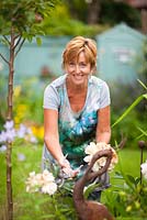 Angie Barker, garden designer deadheading Peony in her garden 
