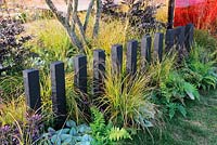 Ferns and grasses along dividing fence using painted timber posts. Description: Prehistoric Modernism. Designer: Alex Schofield