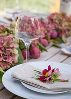 Table place setting with hydrangea, cosmos bipinnatus 'Antiquity' and plums - Prunus domestica 'Victoria'