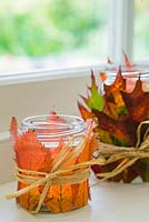 Autumnal Quercus rubra and Prunus leaves used to decorate a candle jars, held in place by Raffia palm. 