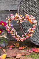 A Euonymus - Spindle heart shaped wreath accompanied with a Riddle and Cosmos flowers