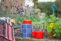 Blanket, thermos flask and a cup of tea, with a view of a raised bed
