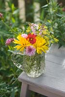 Cut garden flower arrangement - yellow marigolds, crimson flax, pink cornflowers and toadflax in vintage cut glass jug