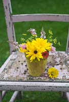 Cut garden flower arrangement - yellow marigolds, crimson flax, fennel and toadflax in yellow flower pot