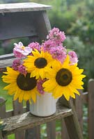 Cut garden flower arrangement - sunflowers pink valerian and Japanese anenomes in vintage wooden steps