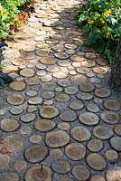 Log pathway leading through vegetable garden. Garden path made from sliced Logs with gravel and sand infill, 