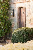 Clipped box and magnolia grandiflora frame the front door of the Elizabethan manor house. 