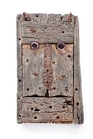 Weathered wood face sculpture on white washed wall 