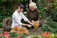 Penny Snell, pictured right, a leading florist and chairman of the National Gardens Scheme, demonstrates and helps Michelle to make a Christmas wreath using a 40cm wire wreath frame, sphagnum moss, spruce, dried pumpkins, rose hips and ribbon.