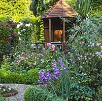 Gazebo overlooks parterre with pebble paths and 4 box edged quadrants filled with roses and perennials. Hand built pergola with roses and clematis. Cordyline and weeping pear.