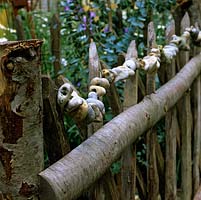 Unusual, seaside-themed wooden picket fence threaded with string of hagstones - sea washed pebbles naturally with hole in middle