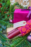Purple coloured Christmas presents accompanied with Fir and Holly - Ilex foliage