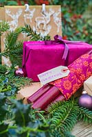 Purple coloured Christmas presents accompanied with Fir and Holly - Ilex foliage