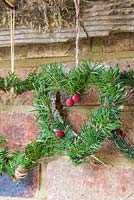 Mixed evergreen hearts hanging on a rustic tool rack. Taxus baccata and pinus