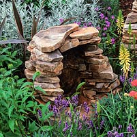 Dry stone water feature crafted from reclaimed Cumbrian stone set in bed of lavender, verbena, kniphofia and Helichrysum italicum.