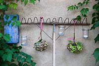 Garden rake decorated with hydrangea flowerheads and tealight candles in jars against a wall