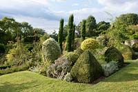 Clipped Buxus topiary, Euonymus fortunei ball, Italian cypress - Cupressus sempervirens with rusted obelisk designed and manufactured by Jane Howard of 'Room in the Garden' on the Cowdray estate.