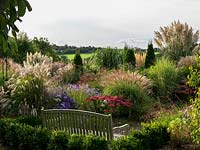 The Anniversary Grass Garden with Miscanthus, Cordaderia, Deschampsia, Stipa, Sedum, Verbena with Aster amellus 'Weltfriede ' and Aster amellus 'King George'.
