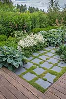 Square paved path surrounded by blue hosta sieboldiana