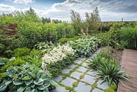 Square slate paving path surrounded by blue hosta sieboldiana and general view ofsumemr border