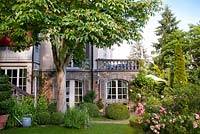 View of te house and garden with borders, mature trees and box topiary. Horse chestnut tree. Marina Wust, Germany