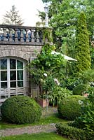 View of the house and garden with borders, mature trees and box topiary. Marina Wust, Germany