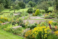 Embedded in a landscape with fruit trees, meadows and a forest, a rural garden plot with perennial borders