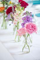 Summer flowers in a cut flower display of bottles as vases for a wedding