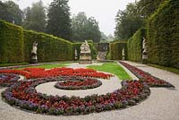 Sculptures in parterre with red Begonia flowers and bordered by deciduous tree hedges in formal garden at the Linderhof palace in late summer, Bavaria, Germany