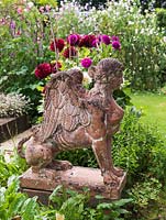 Terracotta sphinx statue keeps watch on kitchen garden with Dahlias 'Requiem' and 'Spartacus' in the background.