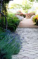 Wide stone and gravel path lined with perennials at Domaine de Cambou, Verfeil, Haute-Garonne, Midi Pyranees, France.